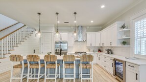 A modern kitchen with white cabinetry, a central island with bar stools, stainless steel appliances, and a built-in oven.