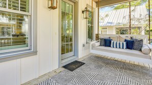 A porch with a white bench, a door with a glass panel, and two wall-mounted lanterns.