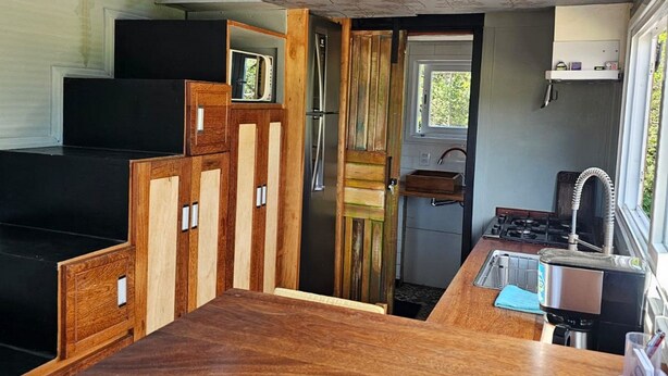 Una cocina compacta con encimera de madera, un refrigerador y un lavamanos.