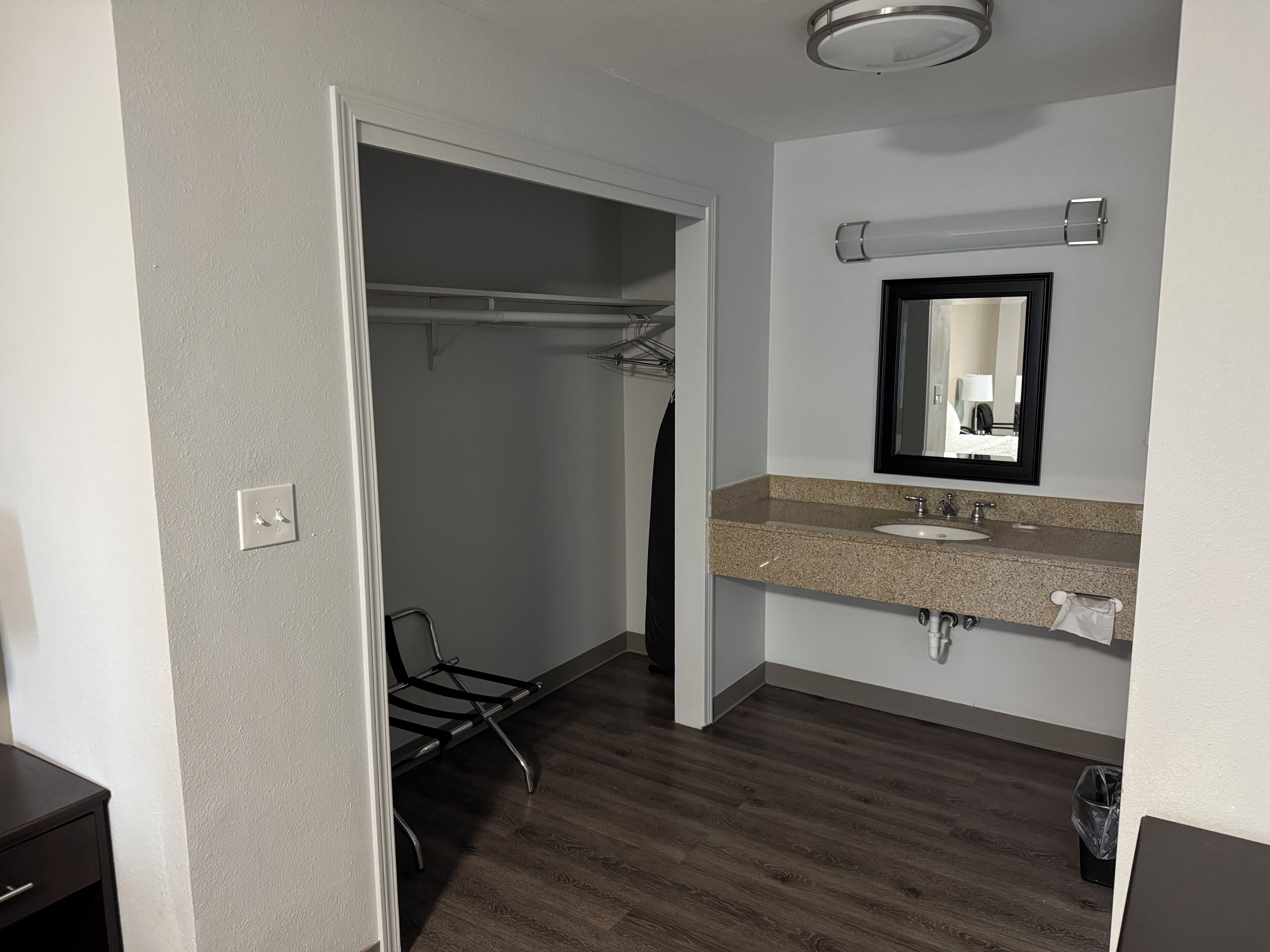 Une salle de bain d’hôtel avec un sol en bois, un lavabo, un miroir et un porte-serviettes.
