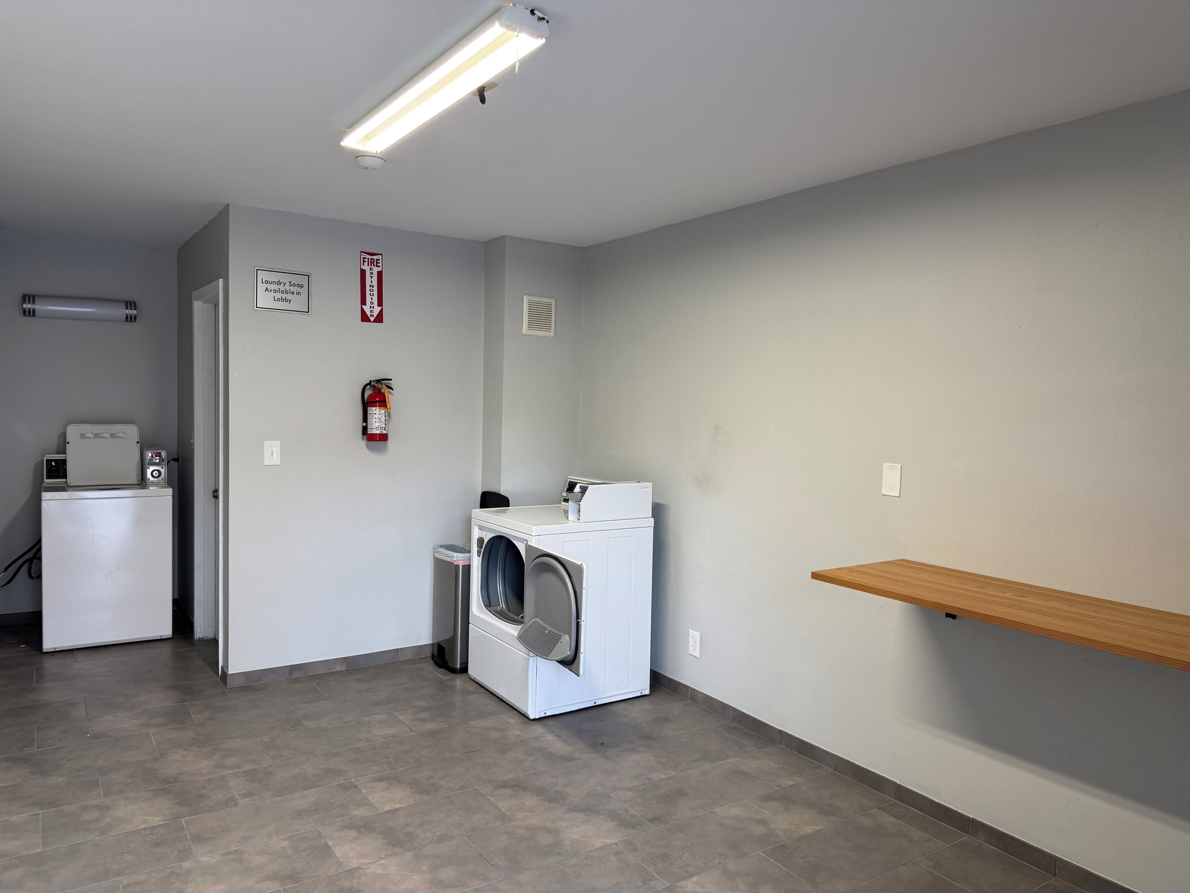 A laundry room with a washing machine, dryer, and a fire extinguisher on the wall.