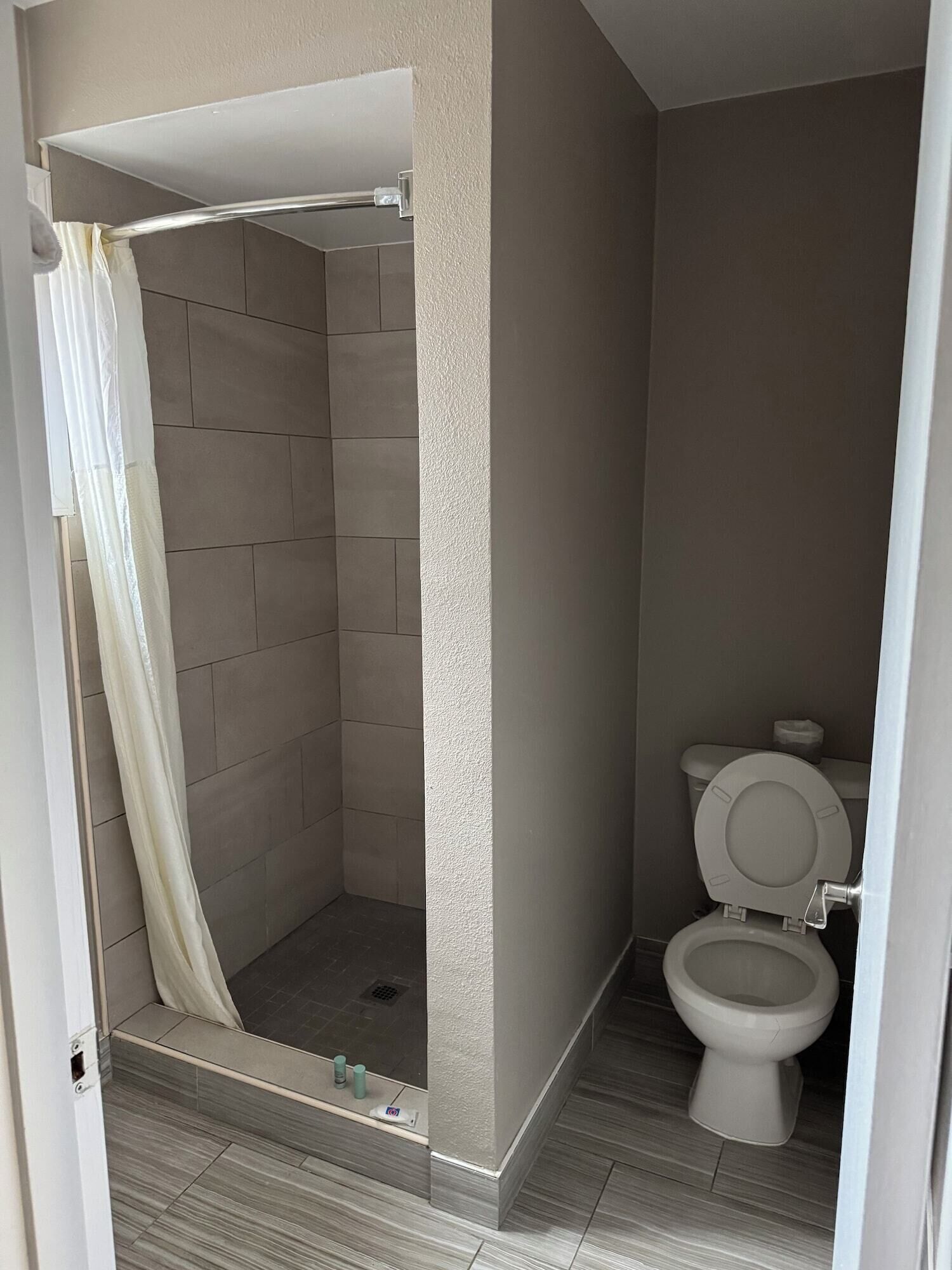 Kylpyhuone, jossa on suihkutila, wc ja laatoitetut seinät.