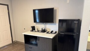 A compact kitchenette with a microwave, coffee maker, and a phone on a counter.