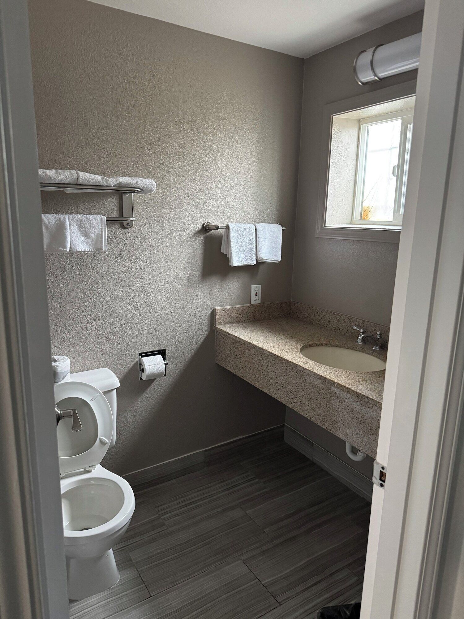Kylpyhuone, jossa on wc, pyyheteline, pesuallas ja ikkuna.