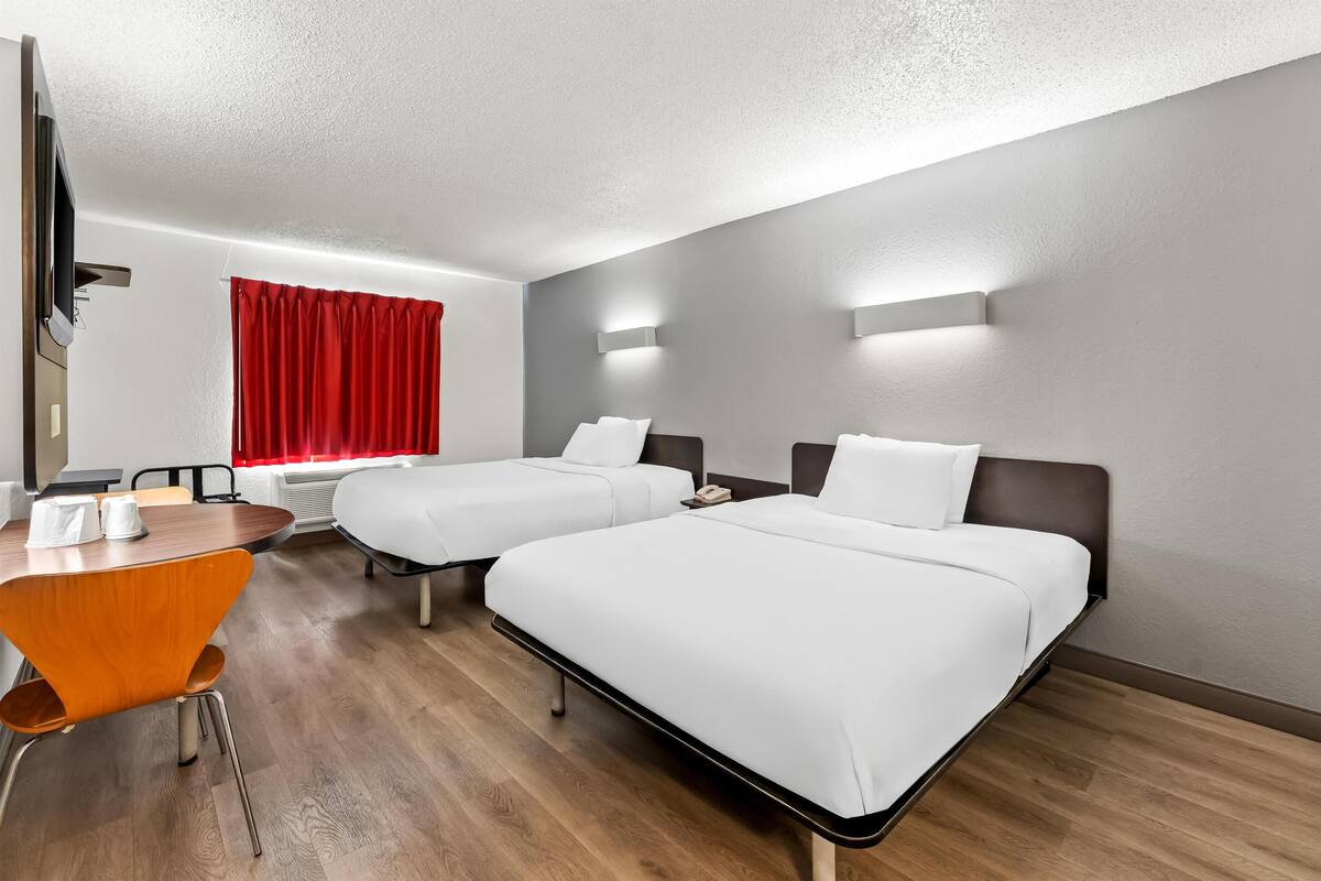 Ein Hotelzimmer mit zwei Betten, einem Esstisch und einem Fernseher.