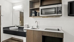 A modern bathroom with a black countertop, two sinks, a coffee maker, and a microwave. - Studio 6 King Of Prussia, Pa - Philadelphia (Wayne)
