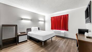 Habitació d'hotel moderna amb llit, taula de nit, escriptori i televisió.