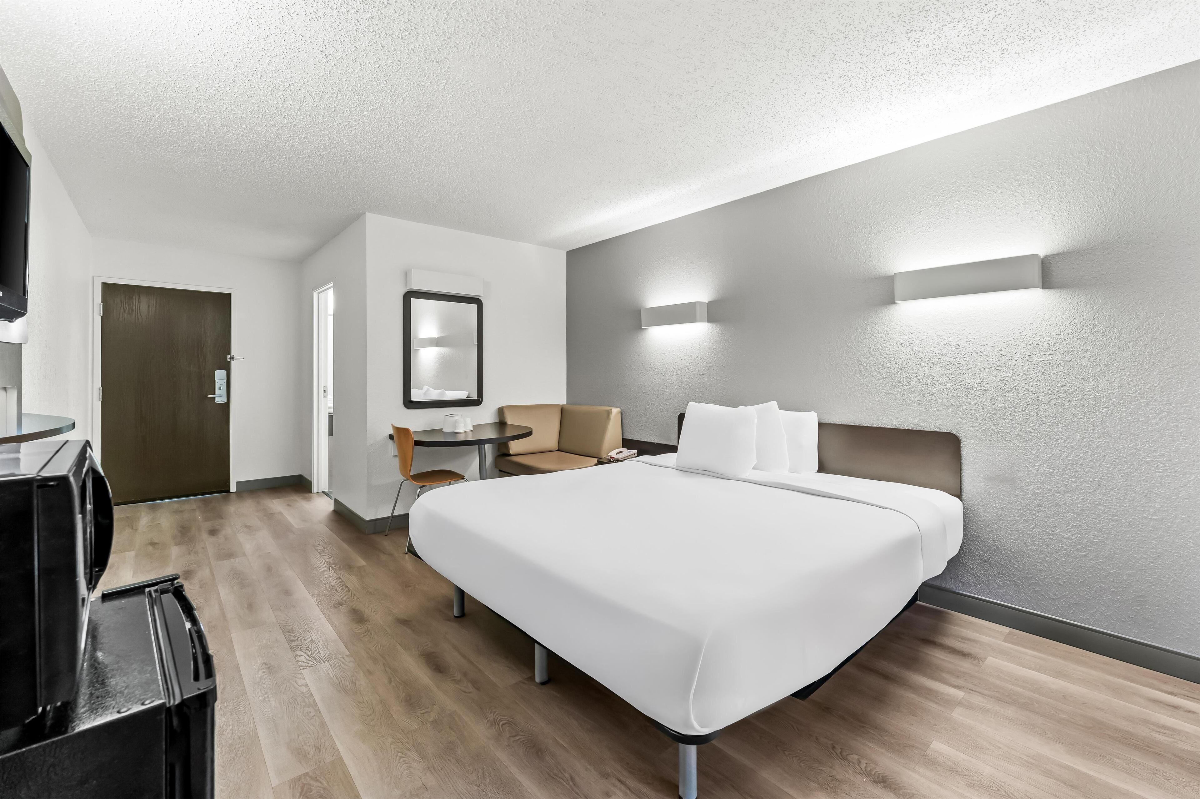 Una habitación de hotel con una cama grande, un escritorio, una silla y un televisor.