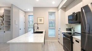 A modern kitchen with a central island, built-in appliances, and a view of the outdoors.