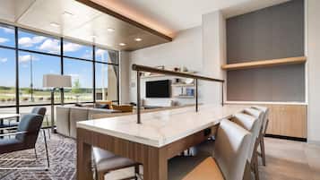 Un intérieur moderne avec une grande table à manger, des sièges et un téléviseur.