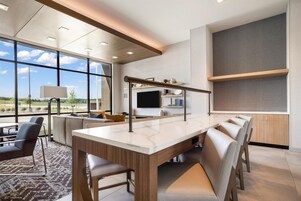 A modern interior with a large dining table, seating, and a TV.