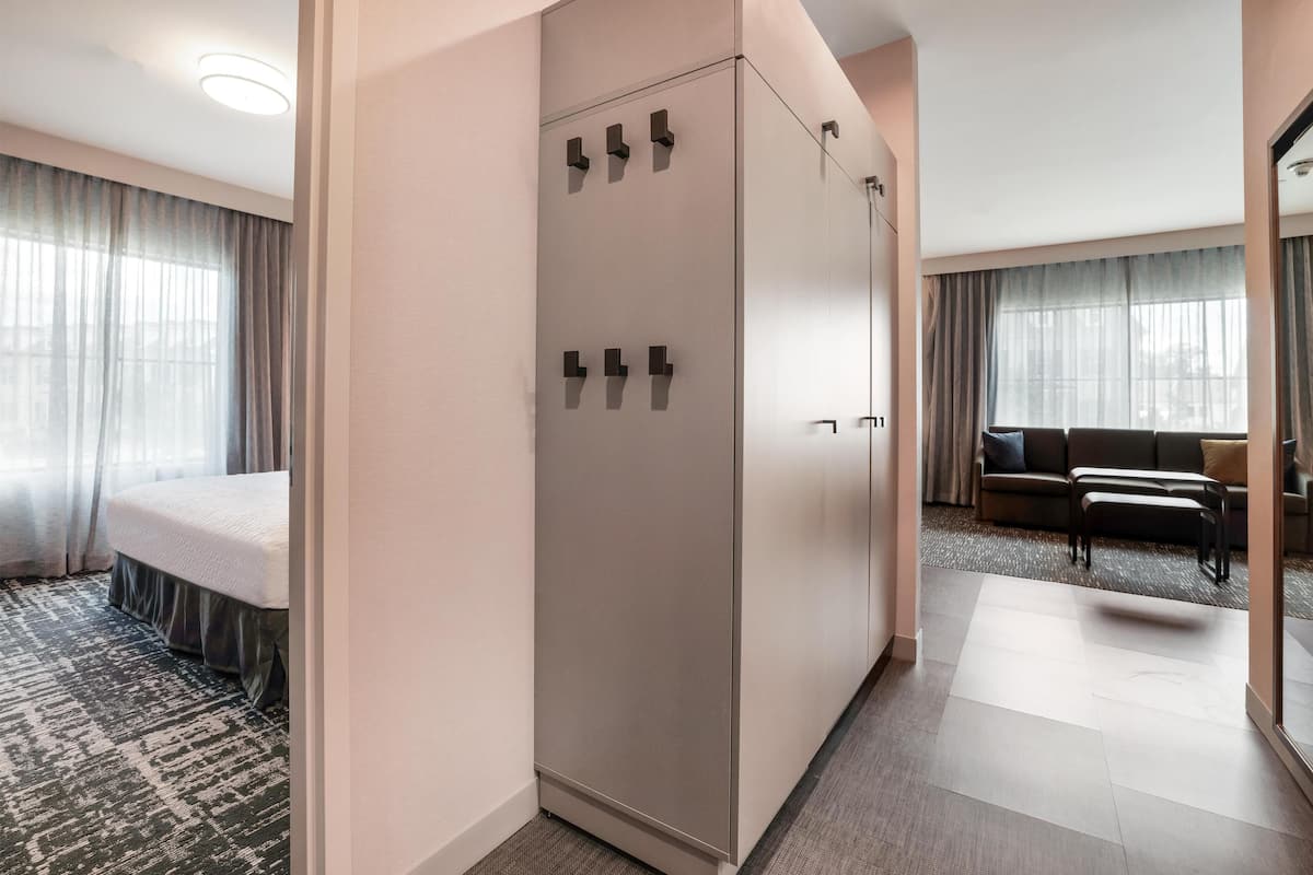 A hotel room with a bed, wardrobe, and seating area.