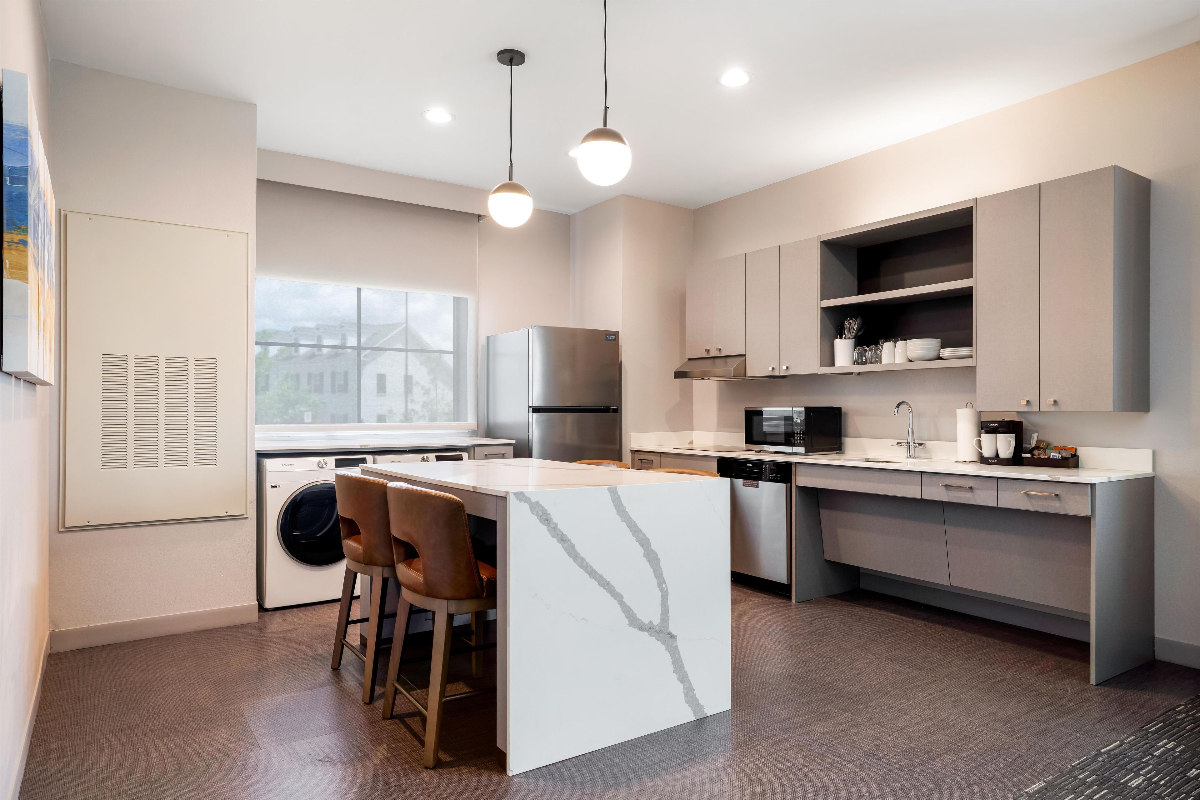A modern kitchen with a central island, stainless steel appliances, and pendant lighting.