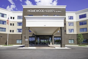 A hotel entrance with 'Homewood Suites by Hilton' signage, a flag, and a clear sky. - Homewood Suites By Hilton Madison Huntsville (Madison)