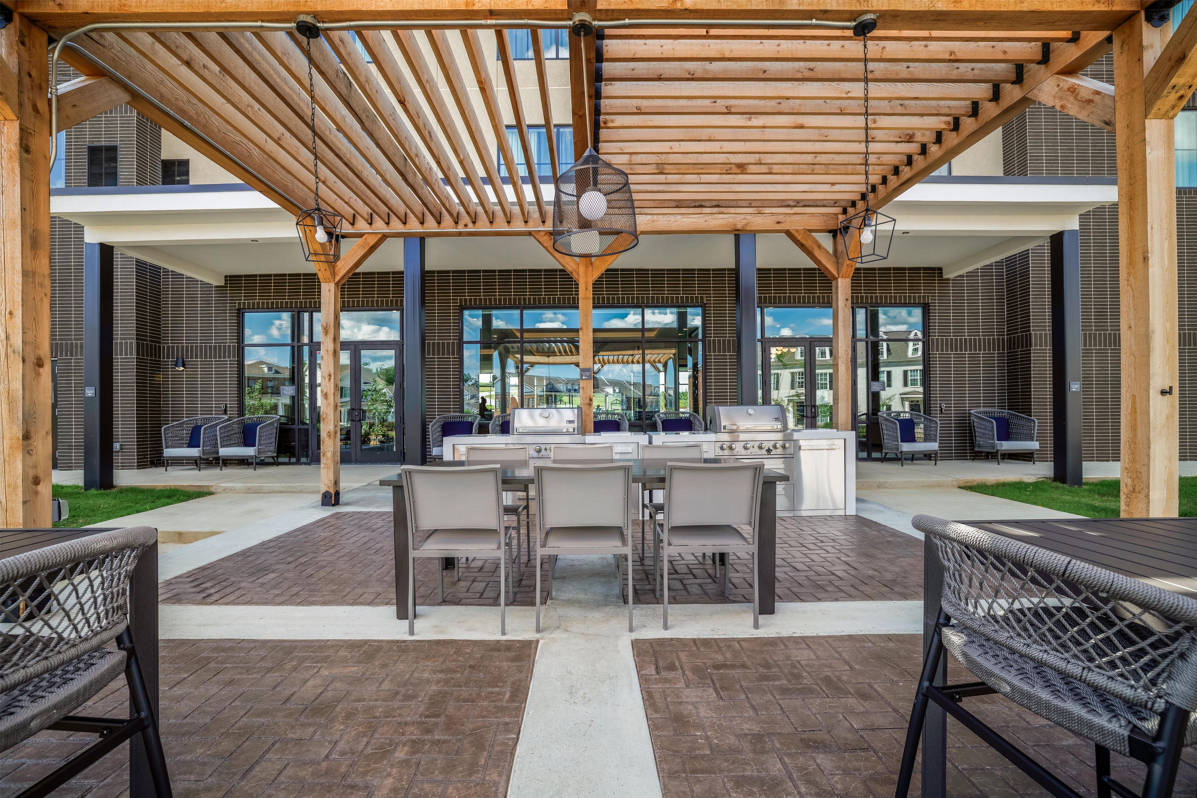 An outdoor patio with a pergola, seating area, and a grill station.