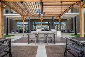 Un patio exterior con pérgola, zona de estar y estación de barbacoa.