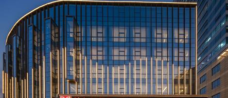 Un hotel moderno con fachada curva, amplias ventanas de vidrio y una entrada bien iluminada.