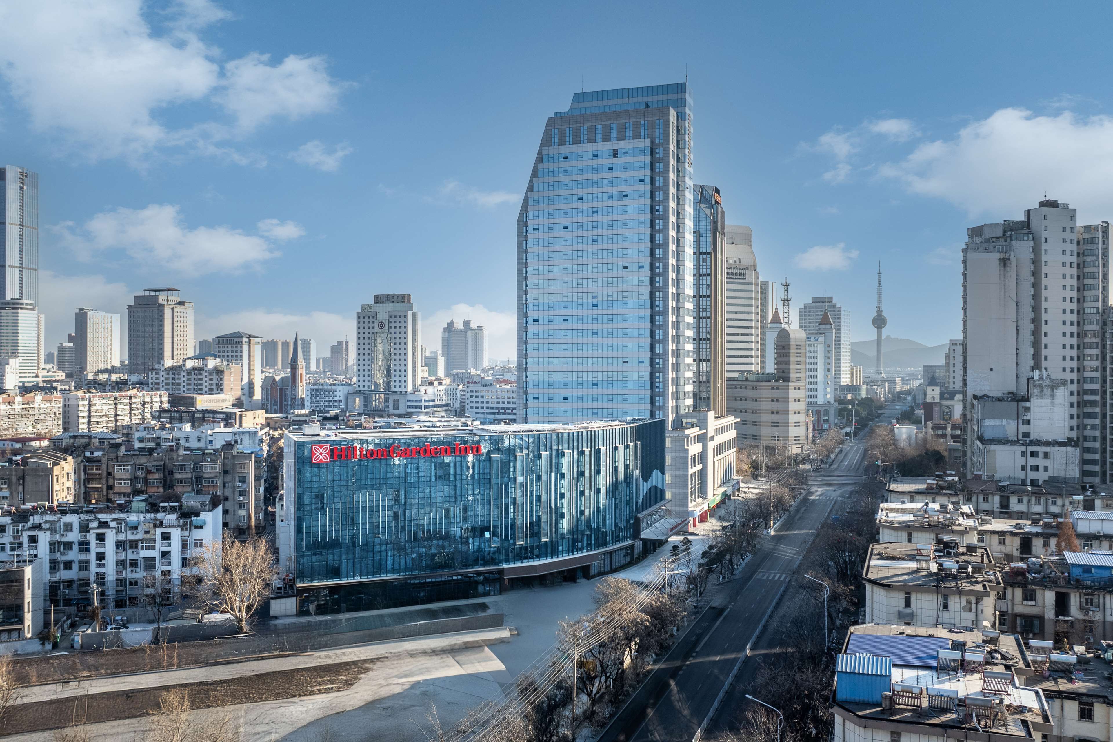 A modern hotel with a glass facade and a prominent red sign.