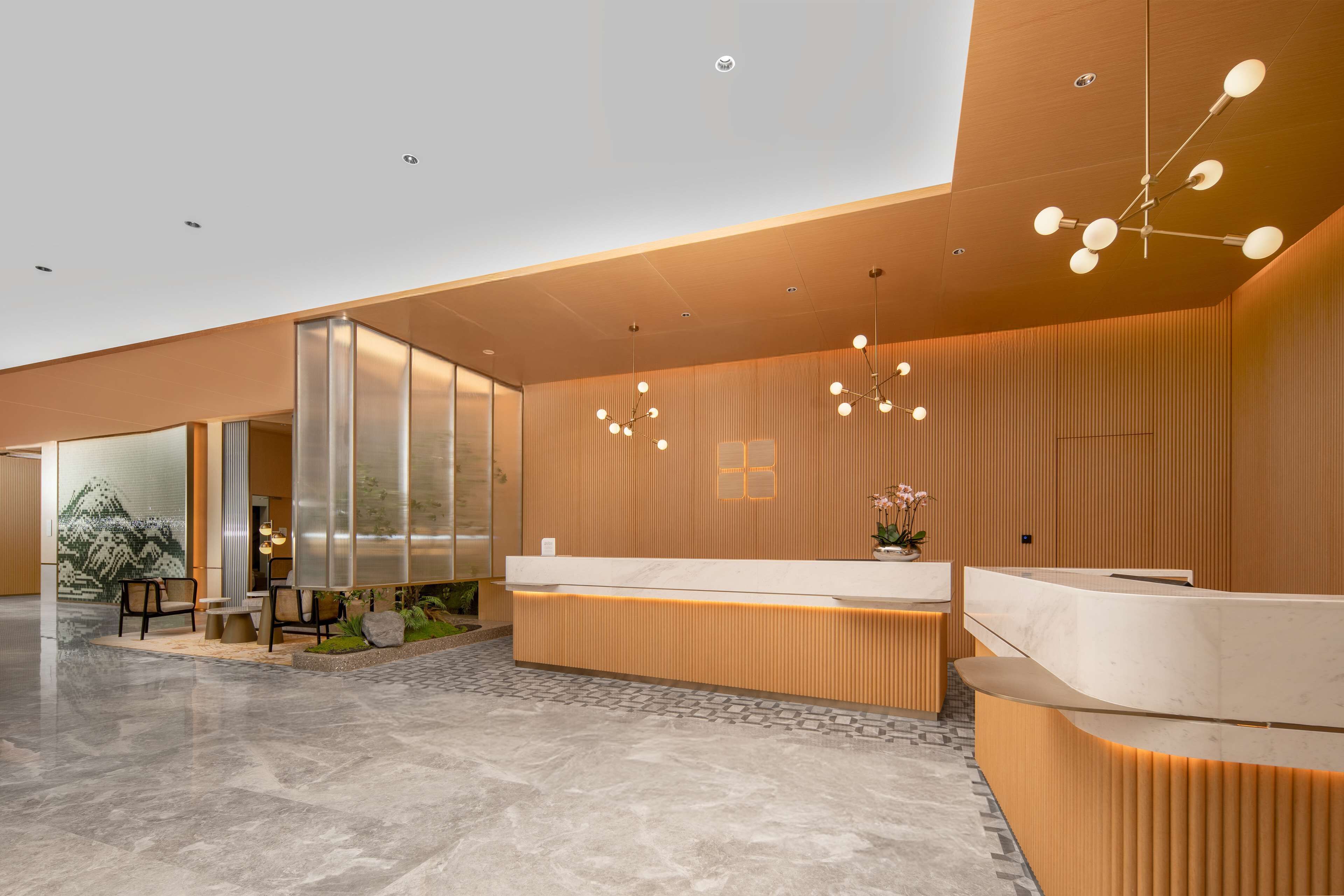 A modern reception area with a wooden reception desk, a seating area with chairs, and a large window.