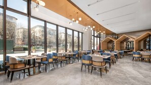 Un vaste espace de restauration intérieur, doté de grandes fenêtres, d’un éclairage moderne et de différents types de mobilier pour créer des ambiances variées.