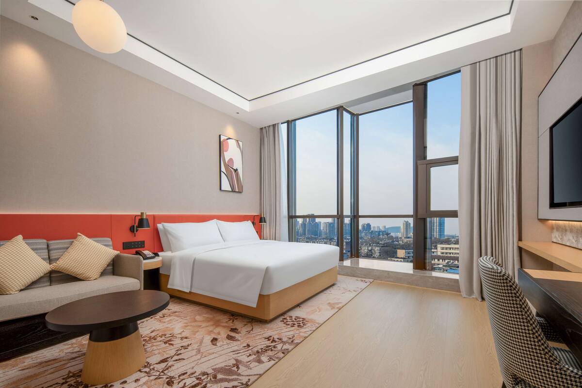 Une chambre d’hôtel moderne avec un grand lit, un canapé, une table basse et un téléviseur.