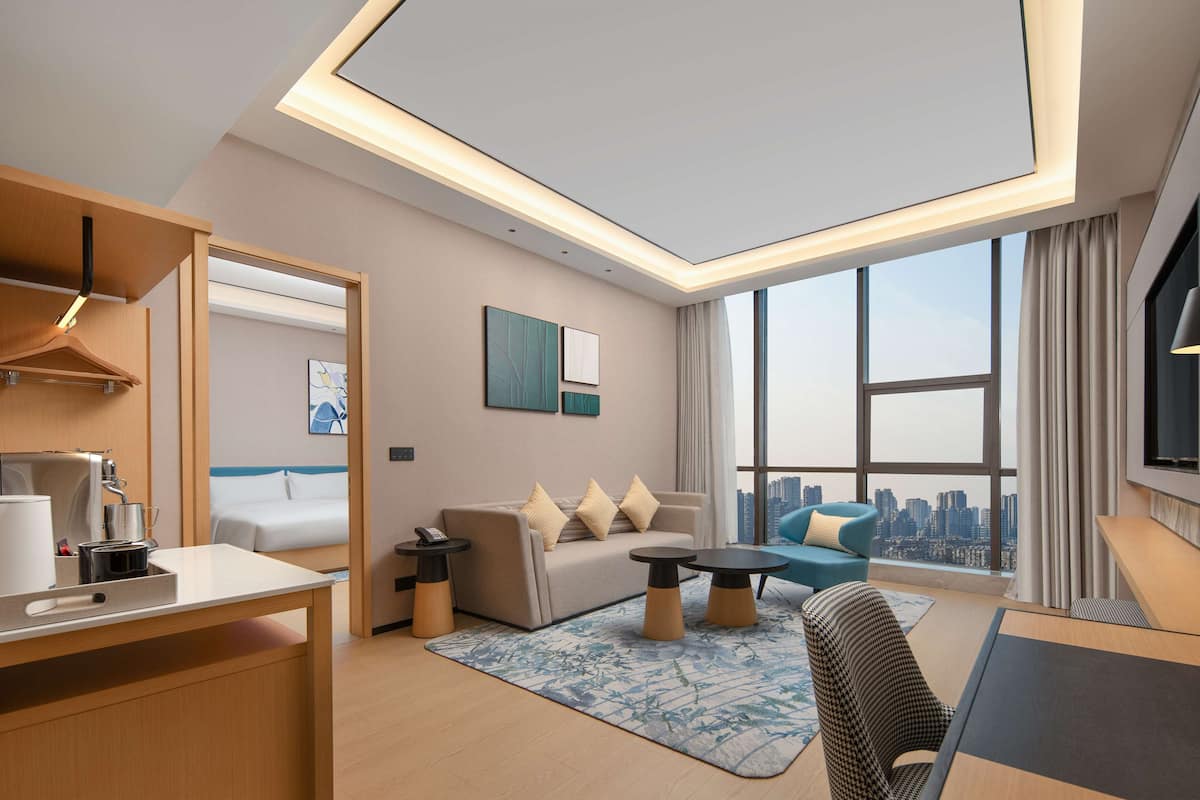 Une chambre d’hôtel moderne avec vue sur la ville, comprenant un canapé, un coin repas et un bureau.