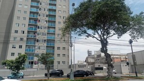 Ein mehrgeschossiges Wohnhaus mit Balkonen, einer von Bäumen gesäumten Straße und geparkten Autos.