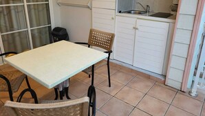A compact kitchen with a dining area, including a table and chairs, a microwave, and a sink. - Au Beau Village Studio Nature View (Sainte-Luce)
