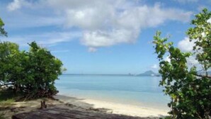 A wooden picnic table on a sandy beach with a view of the ocean and distant land. - Au Beau Village Studio Nature View (Sainte-Luce)