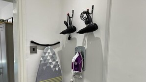Un baño con toallero, secador de pelo y cabezal de ducha en la pared.