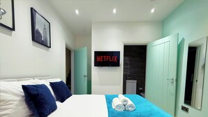 Una habitación de hotel con una cama, una manta azul y un cartel de Netflix en la pared.