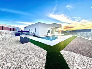 A modern house with a swimming pool, stone walls, and a clear sky. - Modern Mountainside Pool House with Sunset Views on West Side (El Paso)