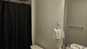 Un baño moderno con inodoro, lavamanos y cortina de ducha.
