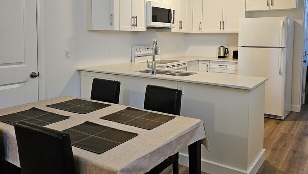 Una cocina moderna con armarios blancos, una isla central, un microondas, una estufa y un refrigerador.