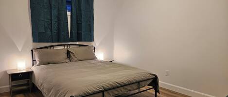 A single bed with a metal frame, two bedside tables, and a window with curtains.