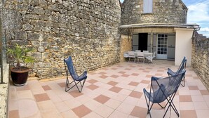 A stone-walled courtyard with a tiled floor, two folding chairs, a table, and a potted plant. - Charming house with panoramic terrace in Domme - Sarlat (Domme)