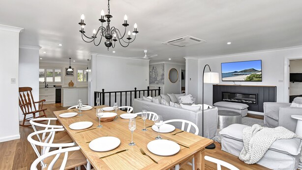 A modern living room with a dining area, a television, and a fireplace. - Kookaburras Holiday House with Pool in Nelson Bay (Nelson Bay)