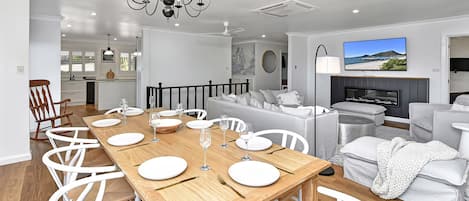 Een moderne woonkamer met een eethoek, een televisie en een open haard.