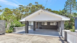A house with a covered porch, stone exterior, and a fenced yard. - Kookaburras Holiday House with Pool in Nelson Bay (Nelson Bay)