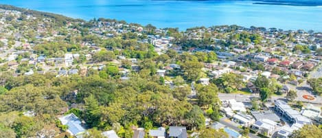 An aerial view of a coastal residential area with houses, roads, and a large body of water.
