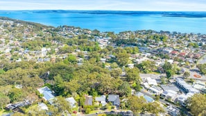 An aerial view of a coastal residential area with houses, roads, and a large body of water. - Kookaburras (Nelson Bay)