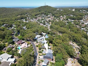 A residential area with houses surrounded by dense greenery, a winding road, and a hill in the background. - Kookaburras Family Retreat in Nelson Bay (Nelson Bay)