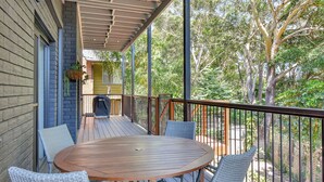 A covered outdoor patio with a round wooden table and wicker chairs. - Kookaburras Holiday House with Pool in Nelson Bay (Nelson Bay)