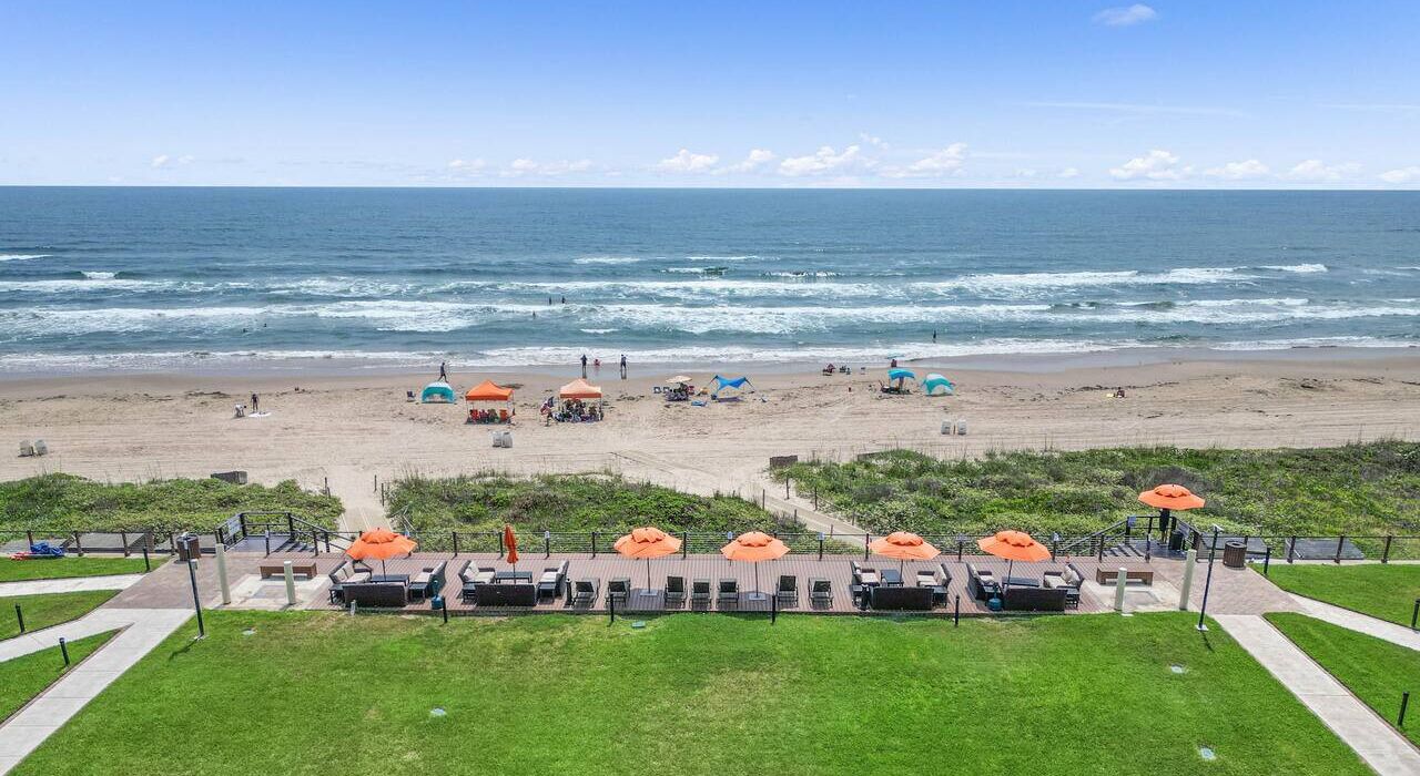 Une plage avec des parasols, des chaises longues et une vue sur l’océan.