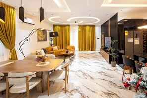 A modern living room with a wooden dining table, yellow curtains, and a sofa with a decorative vase. - Reoky Pads - Redefining comfort and luxury. (Accra)