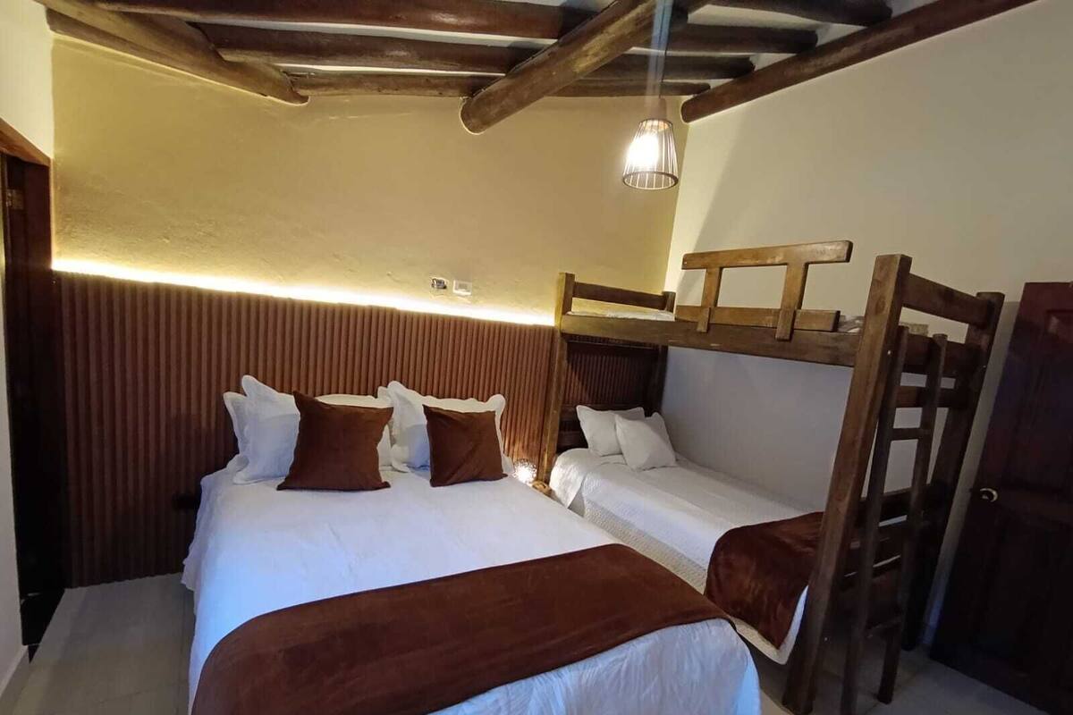 A bedroom with bunk beds, a wooden ladder, and a hanging light fixture.