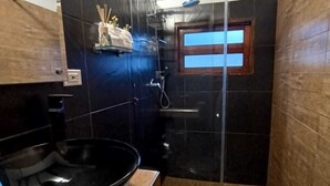 Een kleine badkamer met een zwart toilet, een wastafel en een douchecabine.
