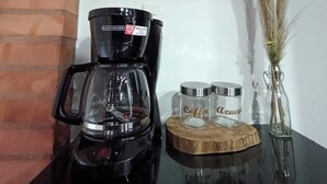 Een koffiezetapparaat op een tafel met twee koffiecontainers en een decoratief object.