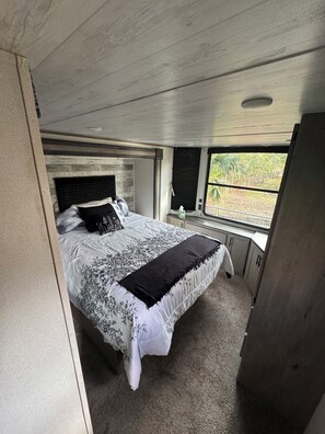 A bedroom with a bed, a window, and a door. - Cozy campground in charming Pierson with AC, WiFi (Pierson)
