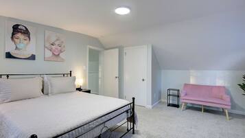 Un dormitorio con una cama, un sofá rosa y dos obras de arte en la pared.